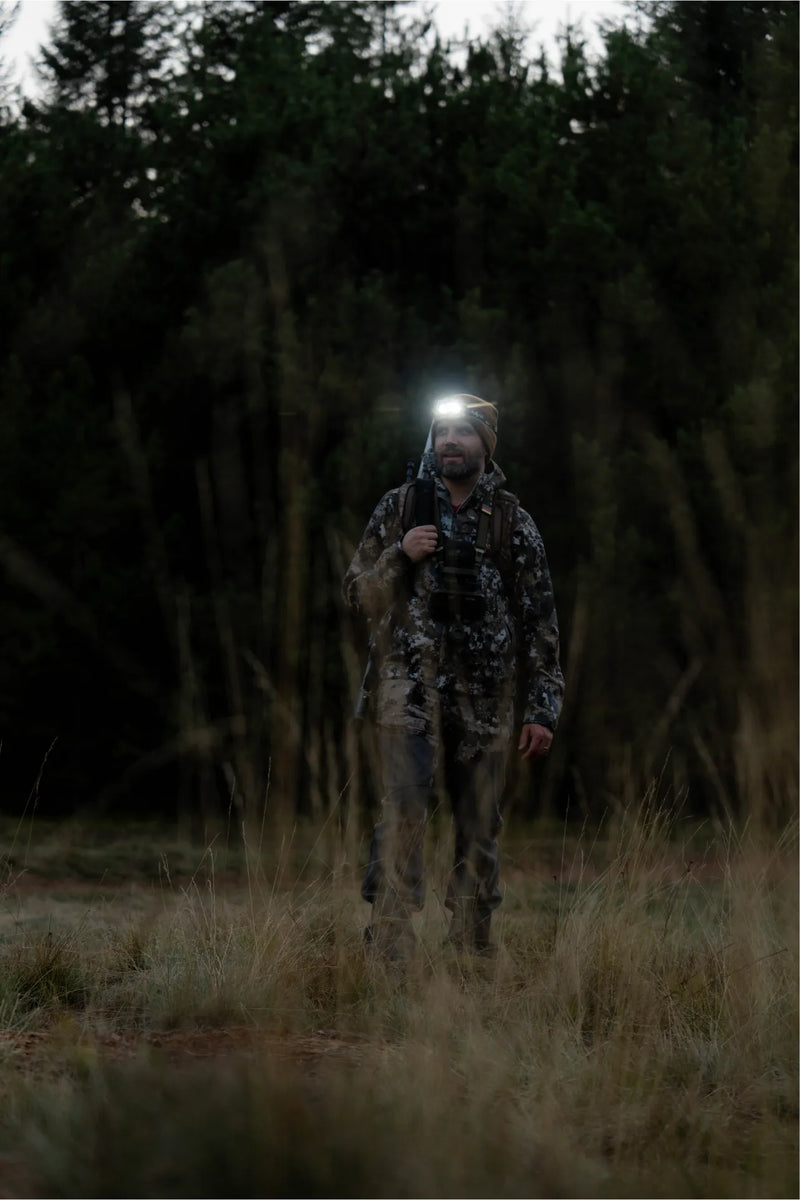 Hunter walking across a field at dusk wearing the HF8R Core RGB