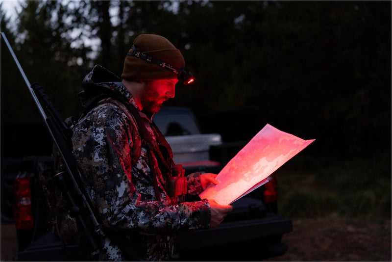 Hunter reading a map by the truck with the red light on
