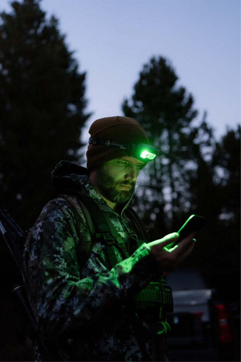 Hunter in the woods using the green light